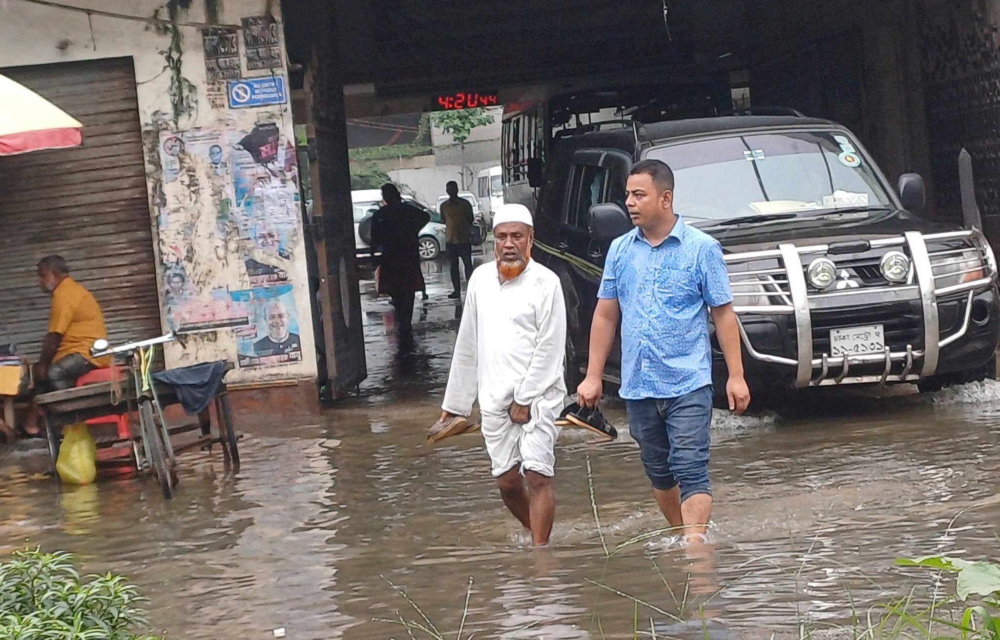 সড়কে জলাবদ্ধতার কারণে অনেক মানুষকে জুতা হাতে নিয়ে খালি পায়ে চলতে দেখা গেছে। স্ট্রিম ছবি