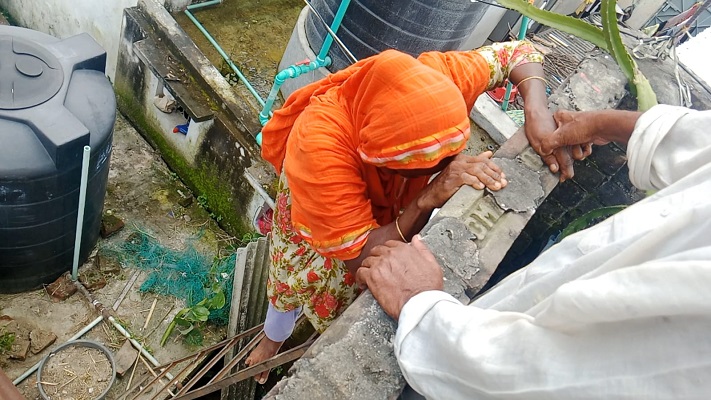 নিজে প্রাচীর টপকানোর পর স্ত্রীকে সহায়তা করছেন আনিসুর রহমান। স্ট্রিম ছবি