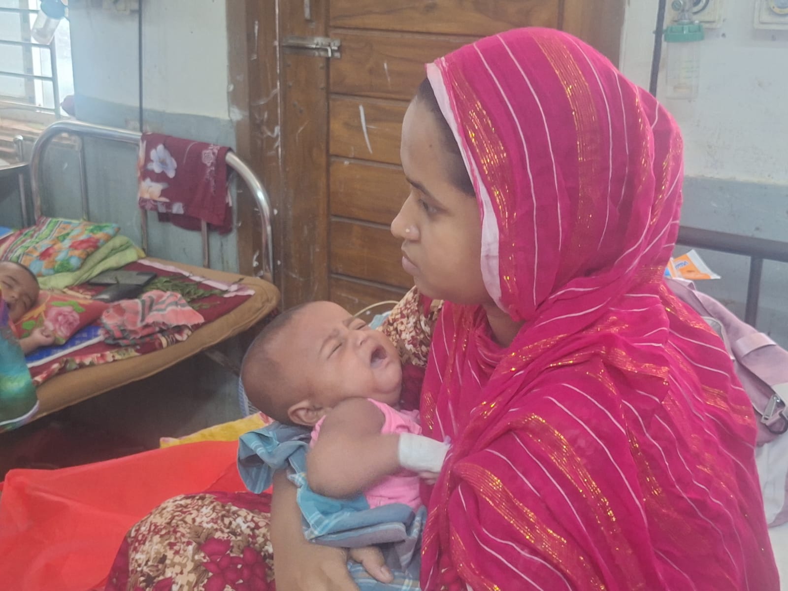 বরিশালের শেবাচিম হাসপাতালে হামের উপসর্গে ভর্তি এক শিশুকে নিয়ে তার মা। স্ট্রিম ছবি