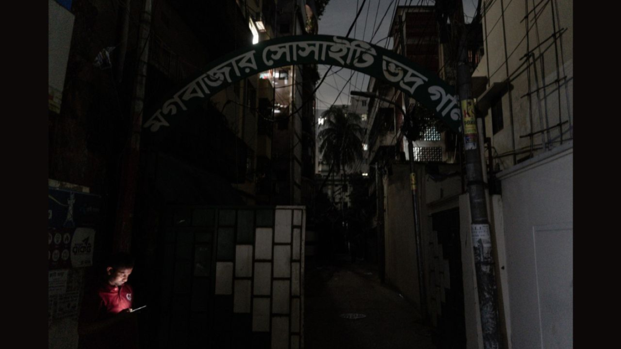 মগবাজারে লোডশেডিংয়ের সময় অন্ধকারে বসে মোবাইল চালাচ্ছেন এক বাসিন্দা। ছবি: সাদিক আল আশফাক
